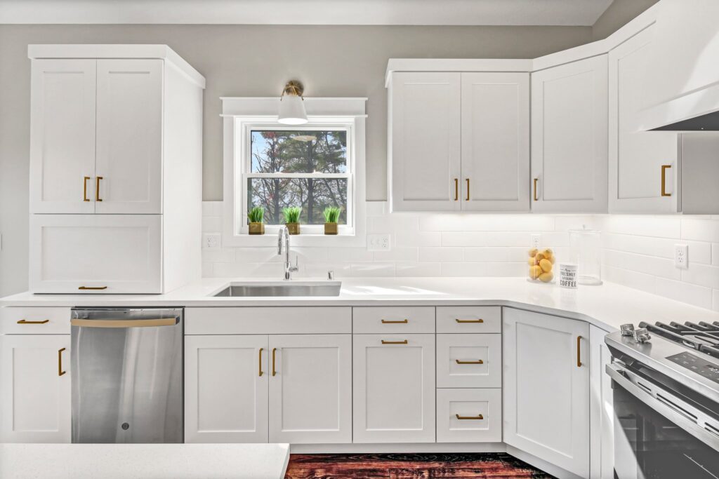 Custom white kitchen cabinets, countertops, kitchen island, and stainless steel stove hood