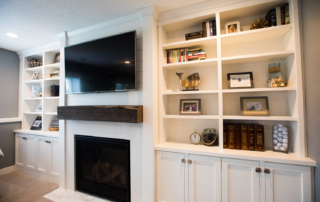 Custom entertainment space cabinets and TV woden console with decorative shelving and fireplace mantle